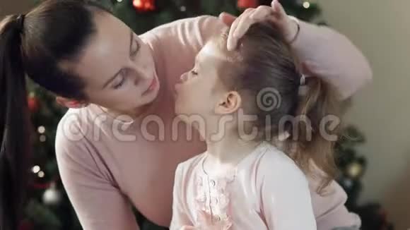 美丽的年轻母女坐在圣诞树旁边的地板上抱着一罐视频的预览图