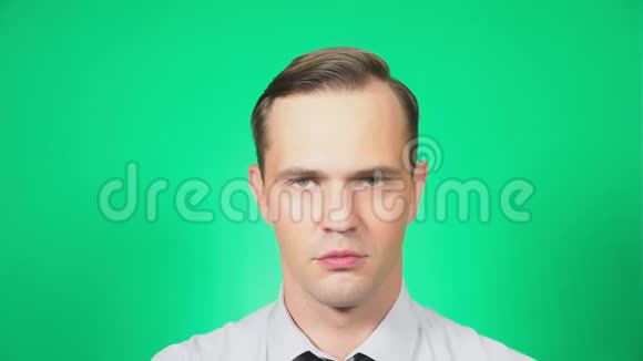 一个年轻英俊的男人的肖像带着误解看着相机绿色背景慢镜头4k视频的预览图