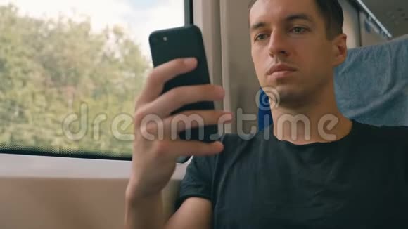 年轻人在火车上使用智能手机录音和滚动视频的预览图