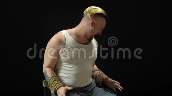 年轻的金发男子绑在椅子上视频的预览图