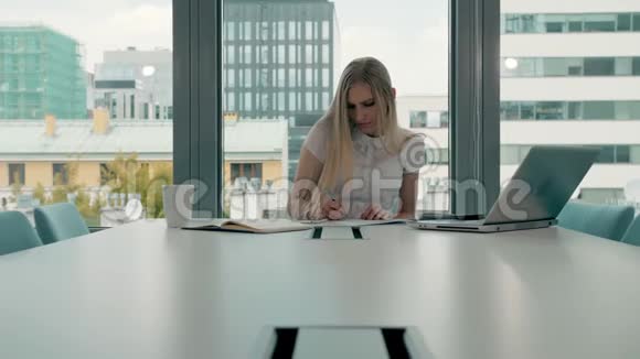 会议室里拿着文件的年轻女商人优雅的金发女人坐在现代办公大厅的长桌旁视频的预览图