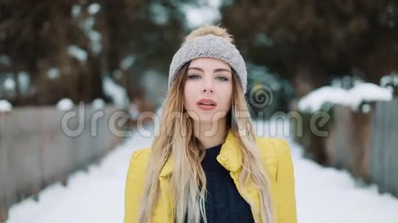 穿着黄色夹克的漂亮女人在雪地上走来走去下雪了户外年轻漂亮视频的预览图