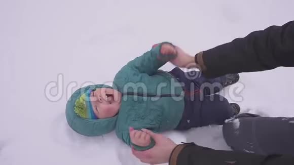 父子俩一个小男孩躺在雪地上爸爸亲他挠他痒痒幸福的家庭每个人都是视频的预览图