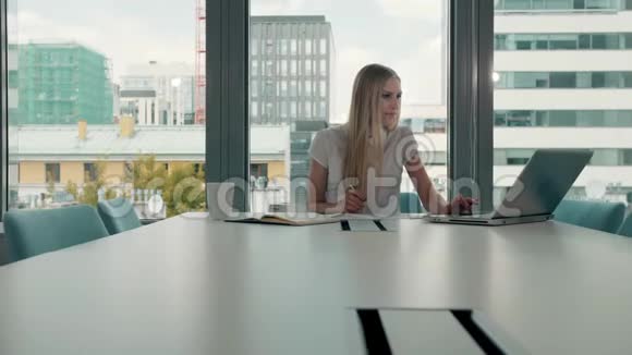 会议室里拿着文件的年轻女商人优雅的金发女人坐在现代办公大厅的长桌旁视频的预览图