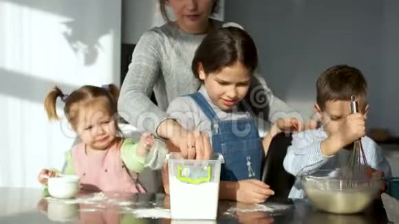 妈妈和厨房里的孩子们三个小朋友揉面团玩面粉开玩笑好玩学会做饭视频的预览图