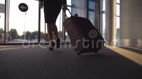 商务女士带着行李通过自动玻璃门离开机场从终点站走出来的年轻女子视频的预览图