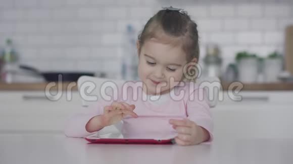 小女孩在厨房里用平板电脑视频的预览图
