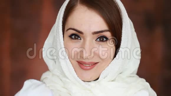 一位年轻而神秘的阿拉伯妇女戴着白色头巾的特写肖像微笑着看着视频的预览图