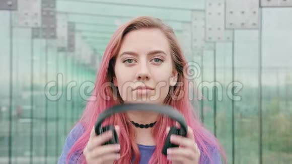 城里戴着耳机的粉色头发的女人视频的预览图