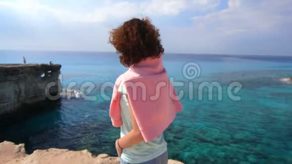 宁静的女人享受岩石海洋景观在海边放松的旅游妇女视频的预览图