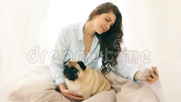 床上的女人和她的小狗狗在自拍录像片段视频的预览图