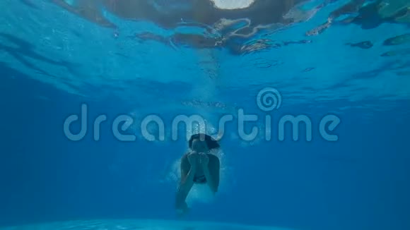 游泳池水下的女孩开放的眼睛在蓝色的游泳池里漂浮在背景气泡上视频的预览图