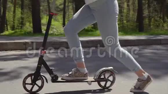 在公园里成年妇女骑着脚踏滑板车在儿童附近骑着溜冰鞋视频的预览图