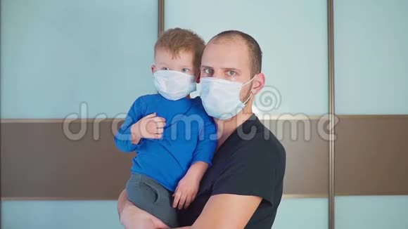 父亲抱着可爱的小婴儿婴儿的肖像孩子戴着保护性医疗面具爸爸和儿子站在里面视频的预览图