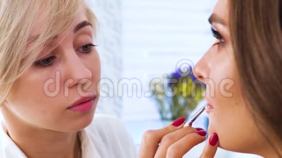 化妆师在年轻女子嘴唇上涂口红视频的预览图