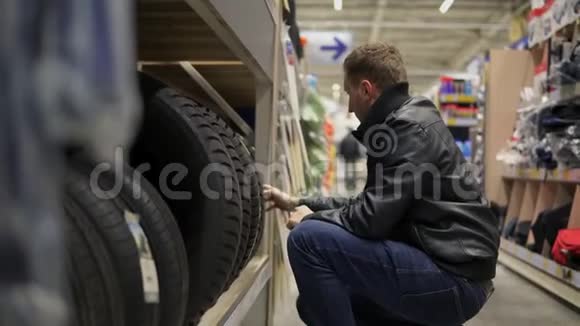 超市里的年轻人选择站在货架上的汽车轮胎视频的预览图