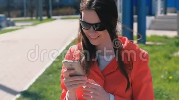 穿着红色外套的幸福女人的肖像等待着某人检查她的手机发短信视频的预览图