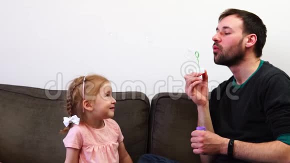 一个漂亮的女婴用嘴抓肥皂泡一个父亲和他的女儿一起度过时光视频的预览图