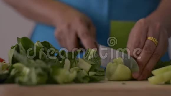 近镜头的女人手切婴儿博克霍伊在木切割板上的健康食品在桌子上视频的预览图