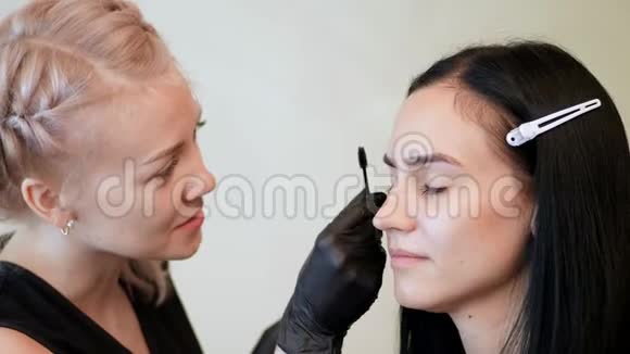 美容院戴黑色橡胶手套的化妆师留着一支特殊的刷子和梳子眉毛师父纠正形状视频的预览图