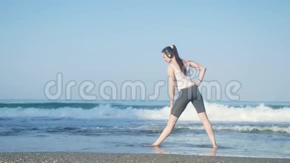 年轻漂亮的女运动员在海滩上做运动视频的预览图