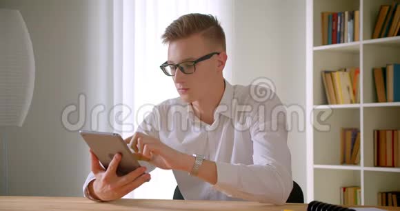 用平板电脑拍摄年轻英俊的白种人商人眼镜的特写肖像并显示绿色的彩色屏幕视频的预览图