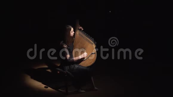 音乐女孩在黑暗的房间里玩班杜拉剪影黑色背景视频的预览图