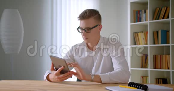 用平板电脑拍摄年轻英俊的高加索商人戴眼镜的特写肖像并用绿色屏幕拍摄视频的预览图