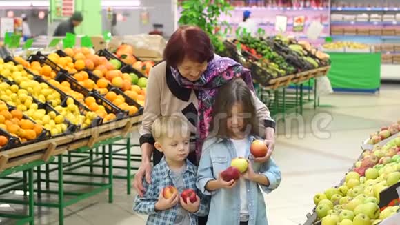 快乐的老妇人带着孙子在超市买水果肖像视频的预览图