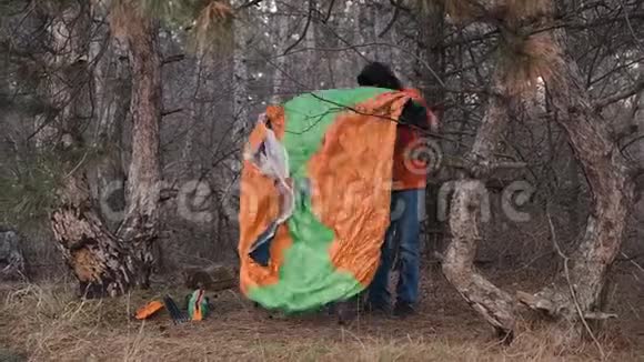 一个孤独的游客穿过松林搭起帐篷过夜视频的预览图