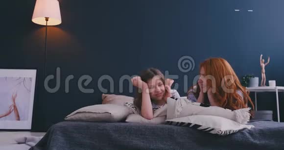 充满爱意的家庭母亲和女儿的孩子女孩在卧室的床上玩耍和拥抱视频的预览图