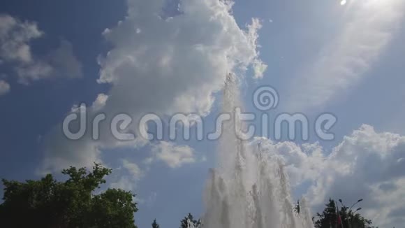 在城市公园里从喷泉喷出的水在无边无际的蓝天上飞舞白云移动视频的预览图