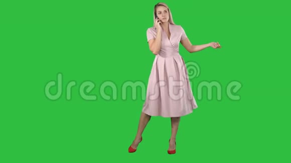 穿着衣服的女人微笑着在绿色屏幕上的智能手机上交谈Chroma键视频的预览图