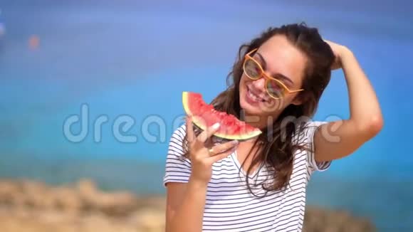 微笑的女人在海滩上慢动作地吃西瓜女性情感视频的预览图
