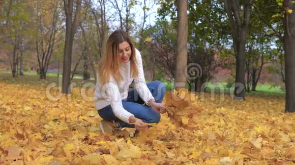 可爱的女人在秋天的公园的花束户外收集秋天的金色叶子视频的预览图