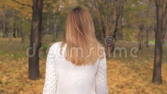 在秋天的公园里女人散步转身欢乐的微笑的电影画面视频的预览图