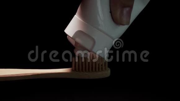 黑色背景下传统环保木竹牙刷上的白色牙膏视频的预览图