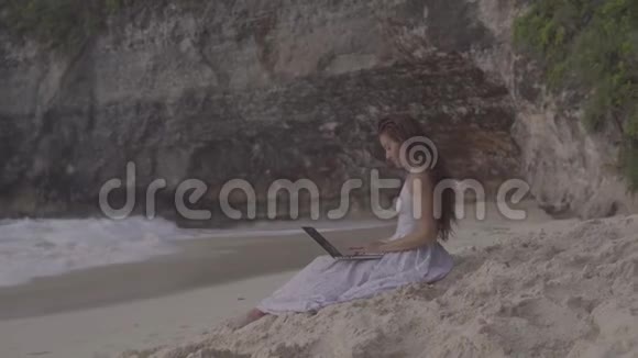 在海滩上用笔记本电脑的年轻女人女自由职业者视频的预览图