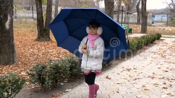 女孩子正在公园里的蓝伞下散步视频的预览图