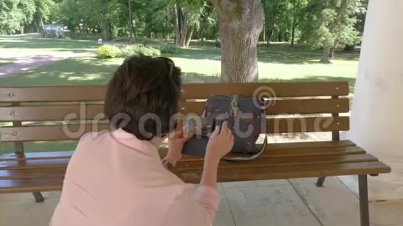 一个黑发女人在智能手机上给她的包拍照视频的预览图