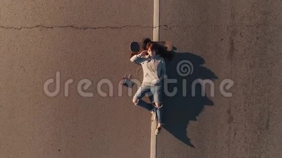空中飞行一个嬉皮士女孩躺在滑板上的画像从上面看视频的预览图