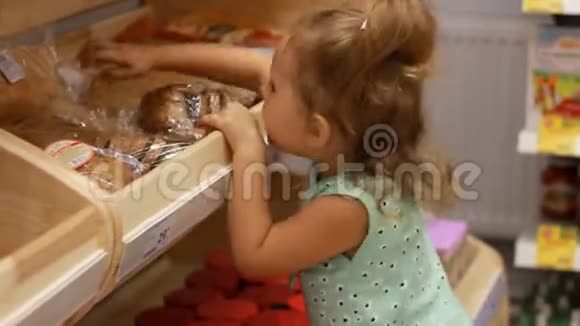 小女孩坐在超市里的手推车里吃食物拿着面包或皮塔视频的预览图