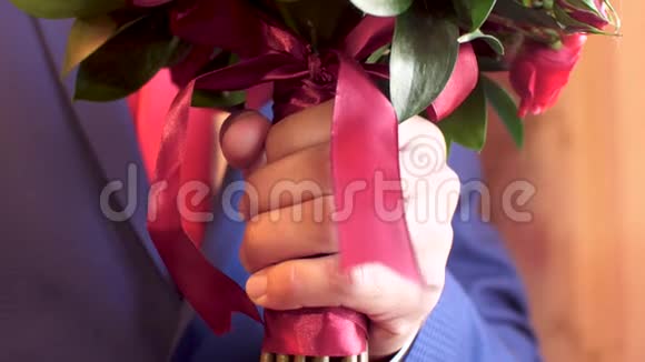 穿着夹克和红色的人手里拿着一束美丽的红玫瑰近点视频的预览图