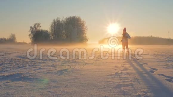 冬天女人跑过田野在夕阳下吹雪飞视频的预览图