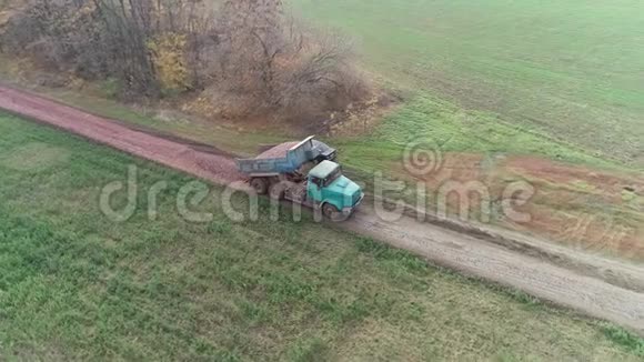 一辆绿色卡车正在乡间道路上抛掷碎石空中射击视频的预览图