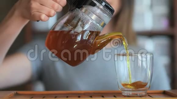 女用手把红茶从玻璃壶倒到小杯特写概念视频的预览图