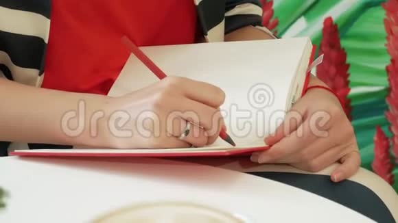 女作家在咖啡馆里创作了一部新作品红笔记本上放着一支铅笔视频的预览图