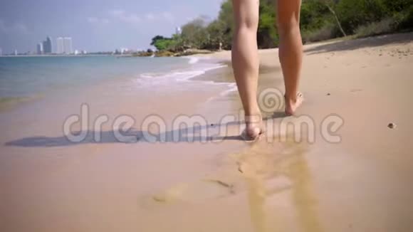女人的腿在沙滩上靠近大海美丽的长而光滑的女人腿沿着沙子靠近4k视频的预览图