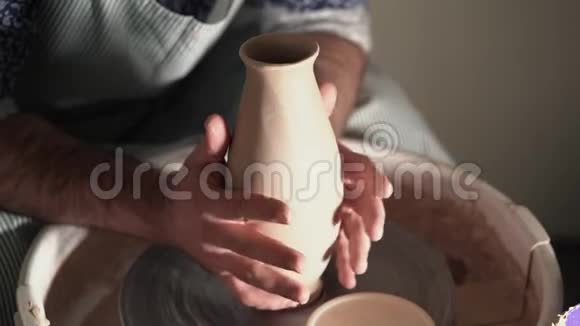 经验丰富的陶工师傅从陶工的车轮上取出粘土花瓶中的成品准备烘烤视频的预览图