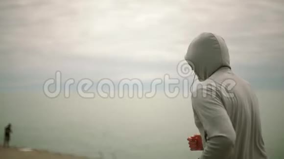 一个年轻的运动员在城市和湖泊的背景下奔跑镜头前侧视慢动作视频的预览图
